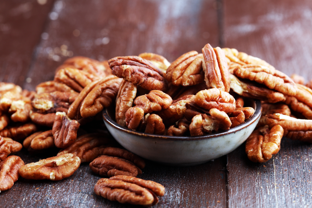 Pecan nuts on a rustic wooden table and pecan nuts in bowl.