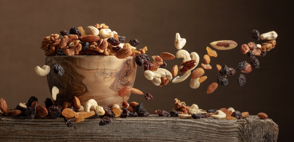 Pecans - Flying dried fruits and nuts. The mix of nuts and raisins in a wooden bowl.